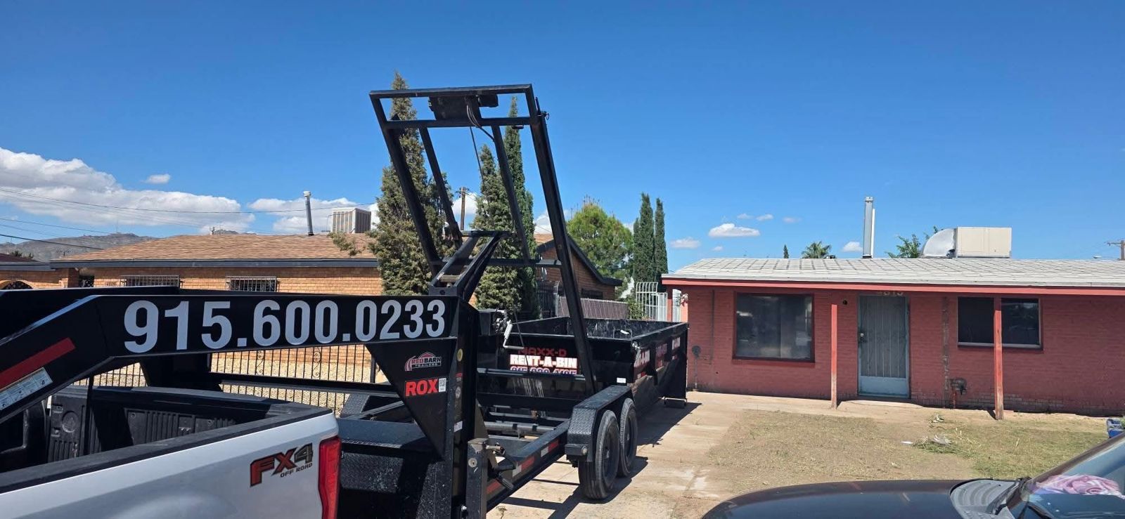 Roadrunner Dumpster truck with container trailer and roll-off frame in front of a home